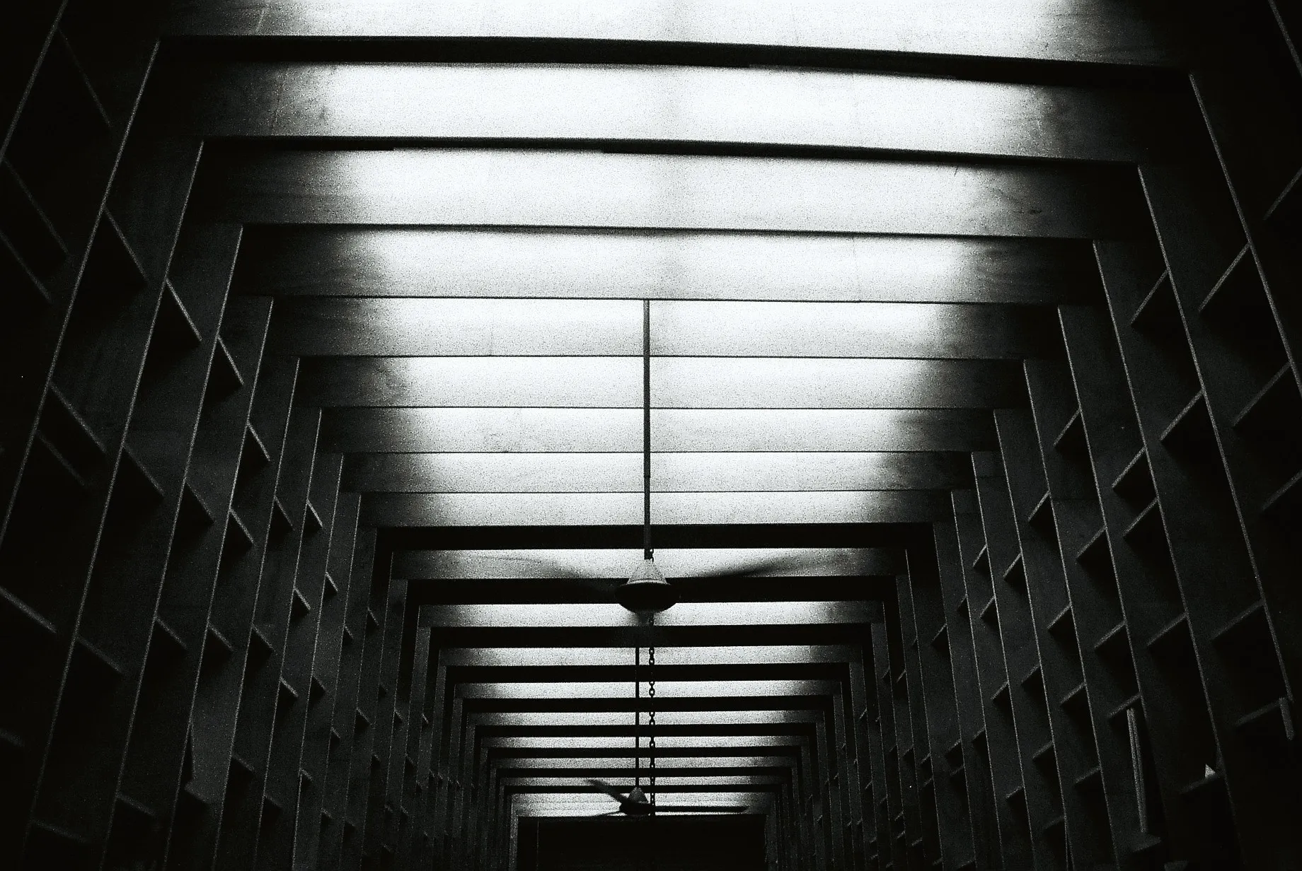 Black and white geometric ceiling structure inside a bookstore corridor with repeating beams and shadows, film photography by Percy Lin 2016